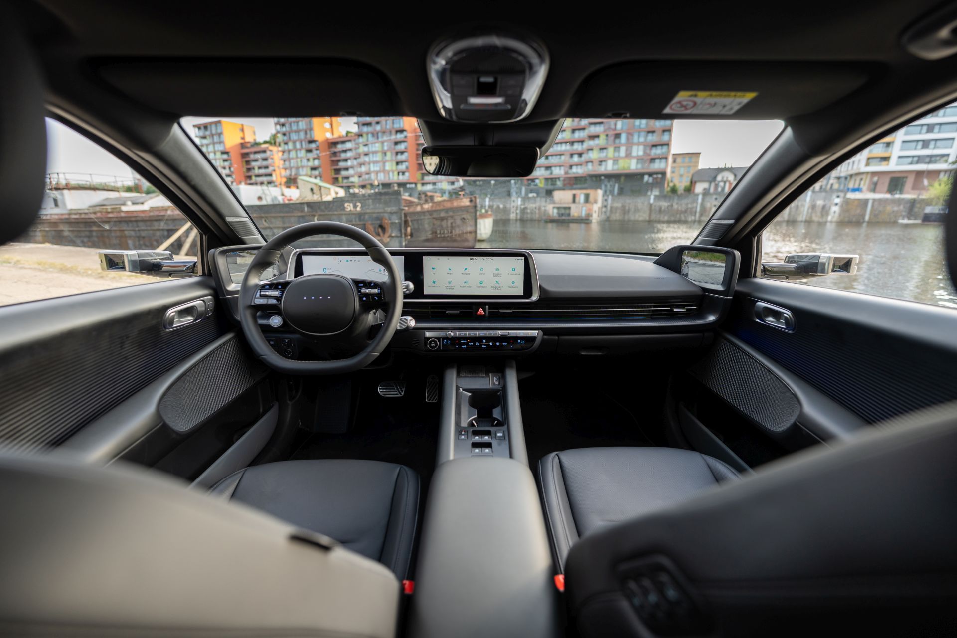 Hyundai IONIQ 6 plně elektrický sedan parkuje na ulici a vedle něj sedí žena.